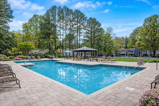 Sandy Springs, GA, Apartments Near Northside Hospital Atlanta - Veridian at Sandy Springs - Swimming Pool With Lounge Chairs, Paved Sundeck, Covered Gazebo, Landscaped Greenery, and Tall Trees.