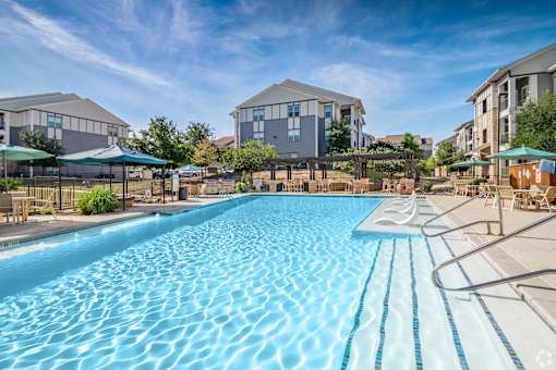A large swimming pool in front of apartment buildings.