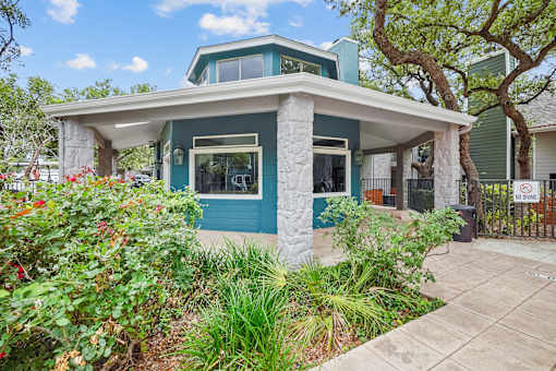 a blue and white bungalow with a tree in the background