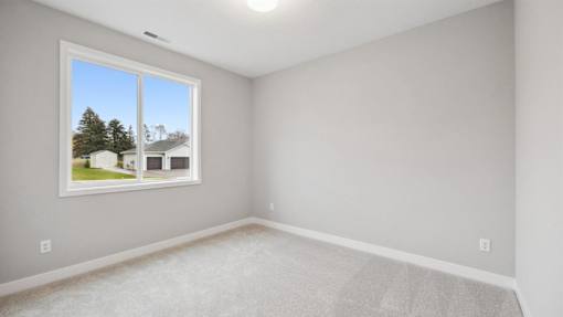 A room with a window showing a view of a house and trees outside.