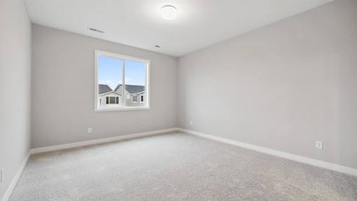A room with a window showing a house across the way.