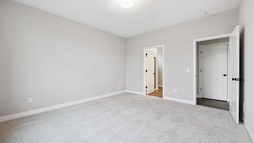 A room with a carpeted floor and two doors.