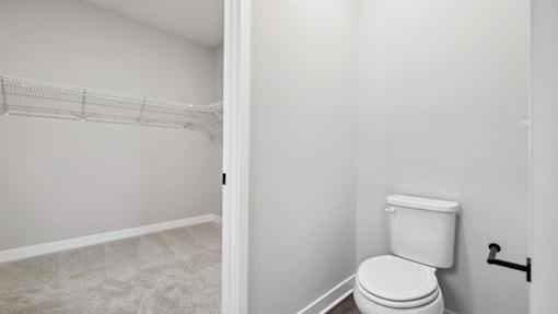 A white toilet in a small bathroom with a white wall and a white floor.