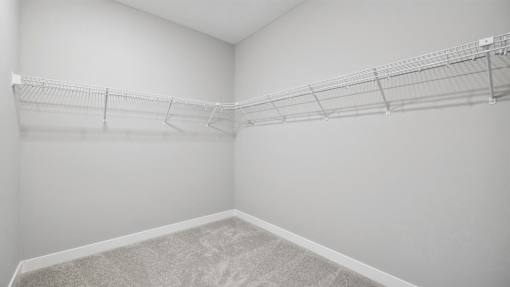 Empty room with a carpeted floor and a metal rack on the wall.
