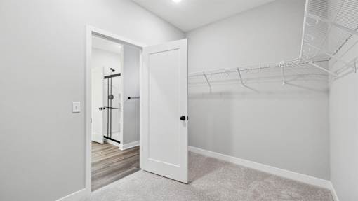 A white door is open to a hallway with a carpeted floor.