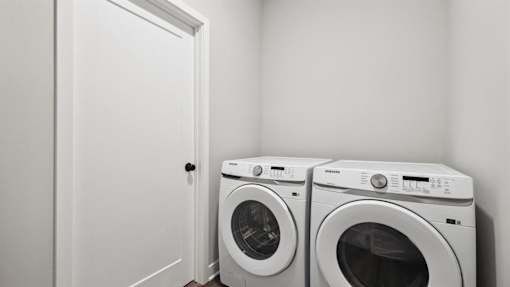 Two white front loading washing machines in a laundry room.