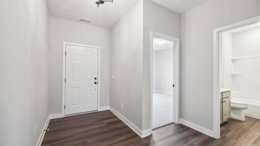 A white door is in the middle of a room with wood flooring.