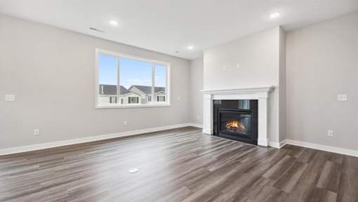 A spacious living room with a fireplace and a large window.
