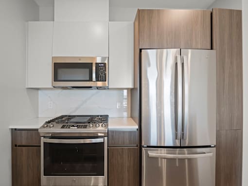 A modern kitchen with a stainless steel refrigerator and a microwave above the stove.