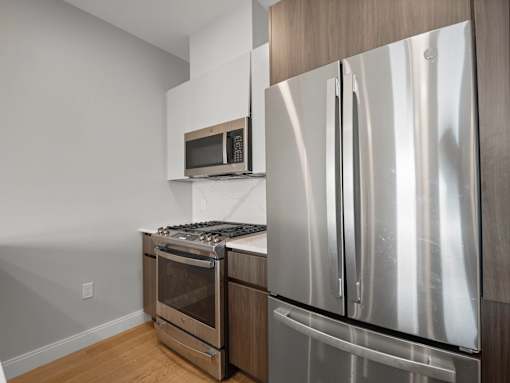 A modern kitchen with a stainless steel refrigerator and a microwave above the stove.