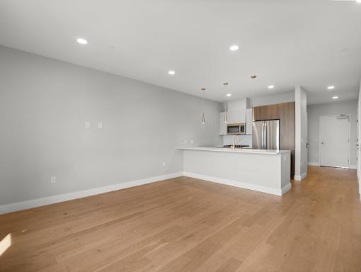 A kitchen with a white counter and wooden floors.