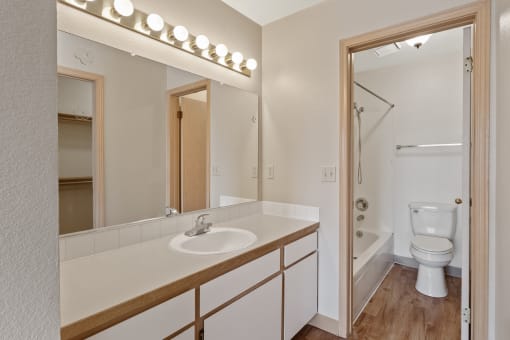 an apartment bathroom with sink and shower and toilet