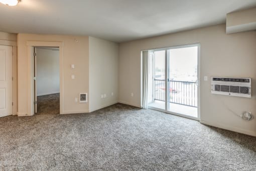 an empty living room with a sliding glass door to a balcony