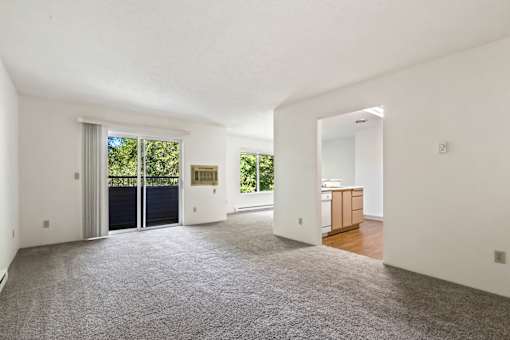 a living room with a door to a kitchen and a carpeted floor