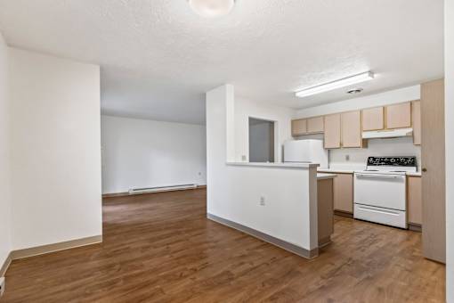 A kitchen with white appliances and wooden floors.