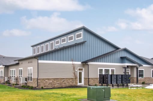 the front of the clubhouse with a blue and gray roof and a green lawn