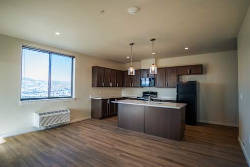 A kitchen with a large island and a window overlooking a mountainous landscape.