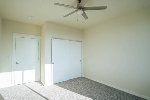 A room with a ceiling fan and two doors.