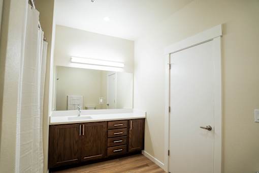 A bathroom with a white sink and brown cabinets.
