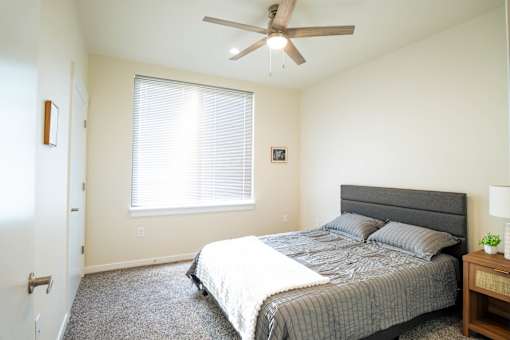 A bedroom with a bed, nightstand, and window.