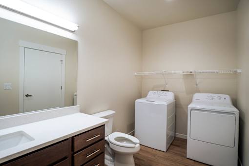 A small bathroom with a toilet, sink, and two washing machines.