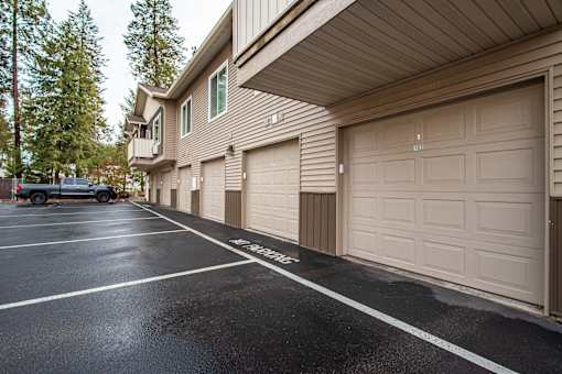 A parking lot with a car parked and a building with garage doors.