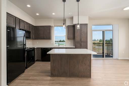 A modern kitchen with a black refrigerator and wooden cabinets.