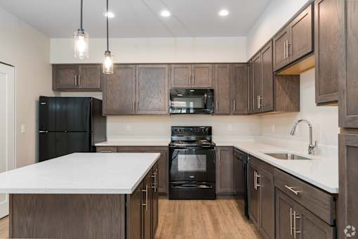 A modern kitchen with dark wood cabinets and black appliances.