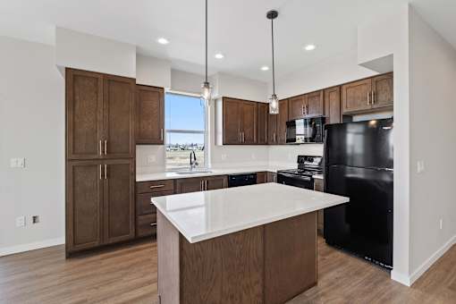 A modern kitchen with a black refrigerator and wooden cabinets.