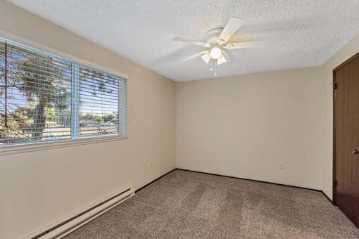 A room with a window and a ceiling fan.