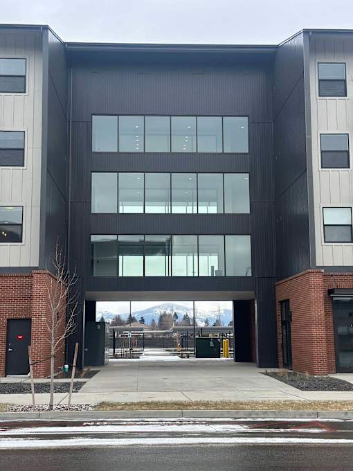 A modern building with a black and grey facade and a glass entrance.