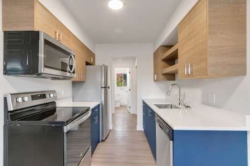 A kitchen with a black oven and blue cabinets.
