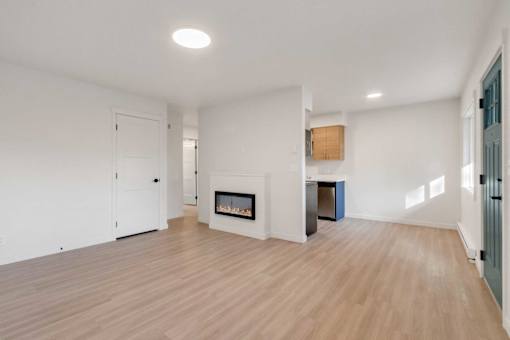 A spacious room with a fireplace and wooden flooring.