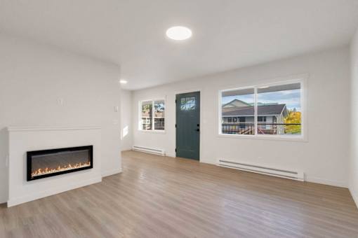A room with a fireplace and a window showing a view of a house.
