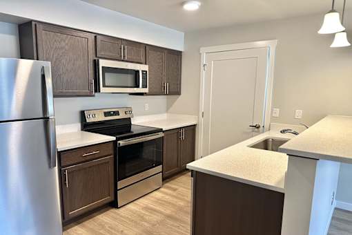 A kitchen with a refrigerator, microwave, oven, and sink.
