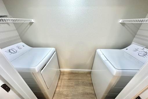 Two white toilets in a small room with wood flooring.