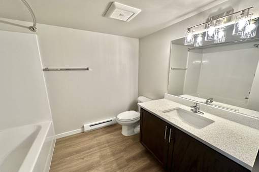 A small, clean bathroom with a toilet, sink, and mirror.