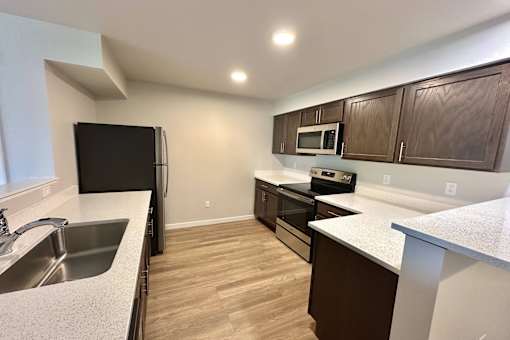 A kitchen with wooden cabinets and a black fridge.
