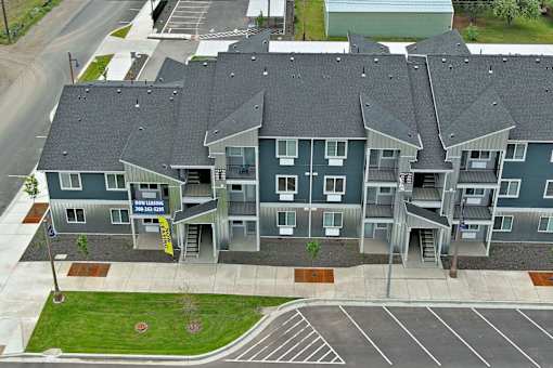 A large apartment complex with a sign that says "Now Leasing".