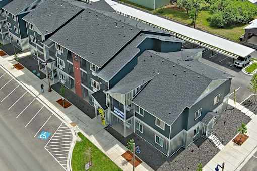 Apartment complex with a parking lot in front.