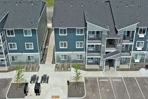 Apartment complex with a parking lot in front.