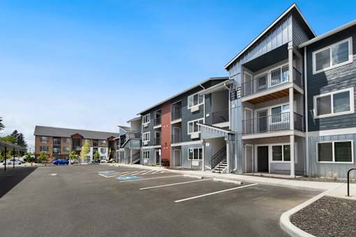 A large parking lot in front of a multi-story apartment building.