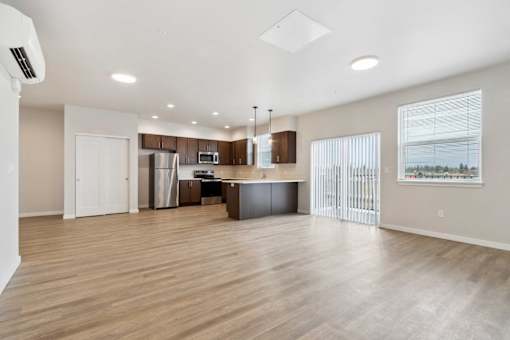 A spacious kitchen with wooden floors and white walls.