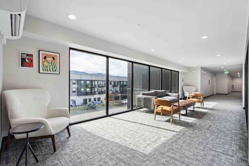 A room with a white chair and a grey carpet.