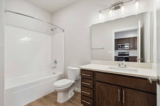 A white toilet is in a bathroom with a white tub and a white sink.