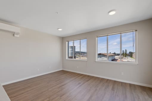 an empty bedroom with large windows and wood flooring
