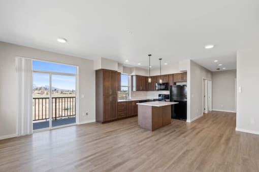 a spacious living room with a kitchen and a balcony