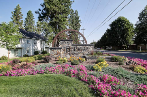 a sign that reads Biltmore Apartments in front of a garden with flowers