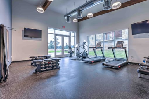 A gym with treadmills, elliptical machines, and a television.