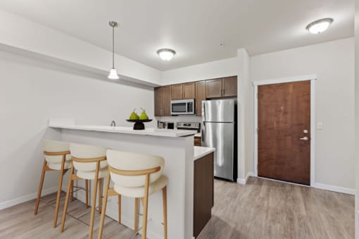 A kitchen with a bar stool and a refrigerator.